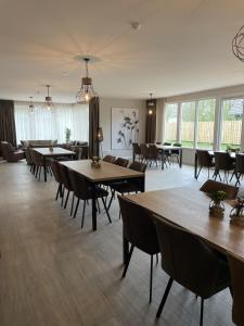 uma grande sala com mesas, cadeiras e janelas em Vakantiehuis B&B Familie Versantvoort em Handel
