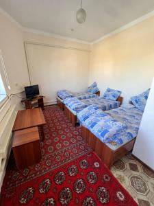 Zimmer mit 3 Betten und einem roten Teppich in der Unterkunft Guest House Medic in Nukus