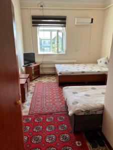 una camera con due letti e un tappeto rosso di Guest House Medic a Nukus