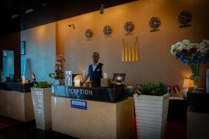 a man standing at a reception desk in a restaurant at Copthorne Hotel Sharjah in Sharjah +37 photos