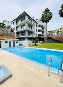 una piscina frente a un edificio de apartamentos en Hillside Haven: Elegant Modern 2 BR Condo w/ Pool, en Funchal