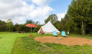ein Zelt mit 2 Stühlen und einem Sonnenschirm in der Unterkunft Spring Lakes lake view bell tents in Nottingham
