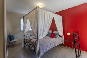 um quarto com uma cama de dossel e uma parede vermelha em Villa - Spa Terre et Mer em Landévant