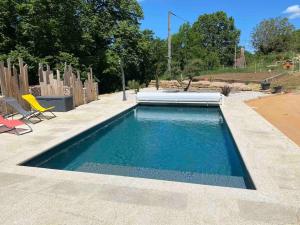 a swimming pool in a yard with a yellow chair at Location saisonnière in Alvignac