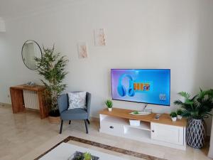 a living room with a flat screen tv and a chair at El Oasis de Roda Golf Apartment in San Javier