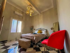 1 dormitorio con 1 cama y 1 silla roja en Noubti en Marrakech