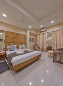 a bedroom with a large bed and a living room at Bentley Hotel, Marine Drive in Mumbai