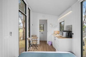 a bedroom with a bed and a kitchen with a microwave at The Stockmans Camp 1 - Sunset Tiny House in Buchan