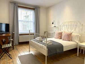 布里斯托的住宿－Harmonious home in the heart of Clifton Village，卧室配有白色的床和电视。