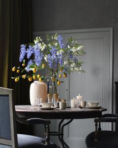 una mesa con un jarrón con flores azules. en Logies aan de Dam, en Middelburg