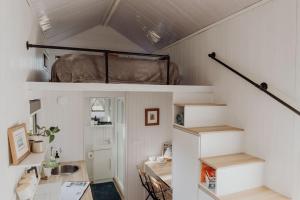 um pequeno quarto com uma cama alta e uma secretária em Noosa Tiny Home em Ringtail Creek