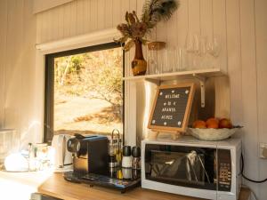 a kitchen with a microwave on a counter with a window at Blue Gum at Aranya Acres in Bungendore