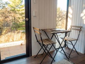 una mesa y 2 sillas en un porche con ventana en Blue Gum at Aranya Acres en Bungendore