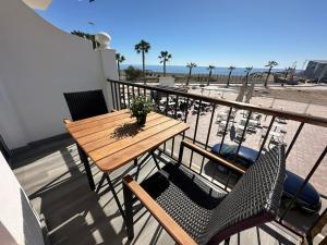 una mesa de madera y sillas en un balcón con vistas a la playa en APARTAMENTO LA CALETA II en Caleta de Vélez
