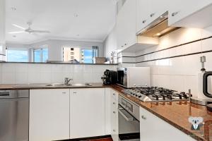 克罗纳拉KozyGuru Cronulla 1 Bed Apt next to Beach的厨房配有白色橱柜和炉灶烤箱 更多4张照片