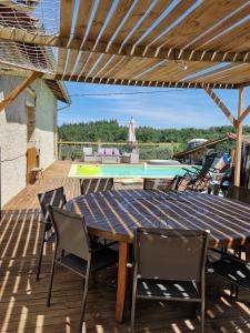 a wooden table and chairs on a deck with a pool at Détente en Pays d'Urfé in Saint-Marcel-dʼUrfé