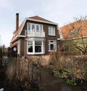 a brown brick house with a white porch at ootmen in Wolphaartsdijk
