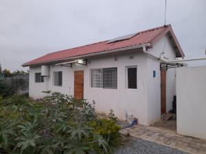 une maison blanche avec un toit rouge dans l'établissement Zambia House, à Lusaka
