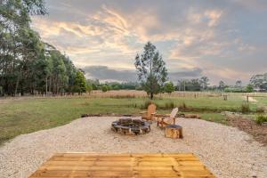 a fire pit and two chairs in a field at Left Field Tiny House in Ashbourne