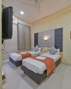 a bedroom with two beds and a flat screen tv at Bentley Hotel, Marine Drive in Mumbai