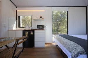 a bedroom with a bed and a kitchen with a counter at Silveroak Lodge Tiny House 