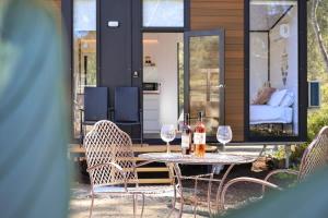 a table and chairs with wine glasses on a patio at Silveroak Lodge Tiny House 