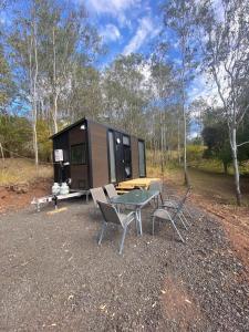 a tiny house in the woods with a table and chairs at Hill Creek 2 Tiny House in Perwillowen