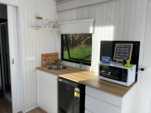 a kitchen with a counter with a microwave and a sink at The Whistling Frog in Neerim South