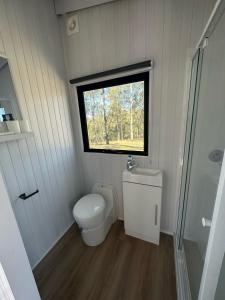 baño pequeño con aseo y ventana en The Retreat Tiny House, en Lagoon Pocket