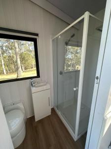 uma casa de banho com um WC e uma cabina de duche em vidro. em The Retreat Tiny House em Lagoon Pocket