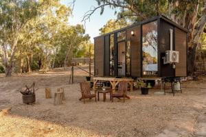 a tiny house in a forest with a table and chairs at Summer Lea 2 in Howes Creek