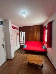 een kamer met een rode bank en een tafel bij Studio Grenal - JK Bem Localizado in Porto Alegre