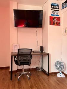 a desk with a chair and a television on a wall at Studio Grenal - JK Bem Localizado in Porto Alegre