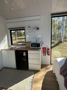 uma cozinha com um balcão com um micro-ondas e uma cama em The Retreat Tiny House em Lagoon Pocket