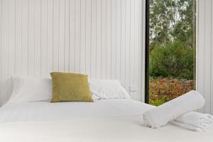 uma cama branca com uma almofada amarela e uma janela em Northern Grampians Getaway em Dadswells Bridge