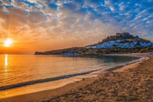 a view of a beach with a hill in the background at Vassos Apartments in Lindos