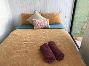 - un lit avec des oreillers et des mitraillettes dans l'établissement Lotties Farm Tiny Homes, à One Tree Hill