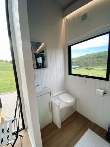 Elle comprend une petite salle de bains pourvue de toilettes et d'une fenêtre. dans l'établissement Lotties Farm Tiny Homes, à One Tree Hill
