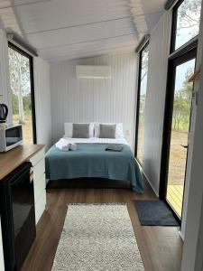 ein Schlafzimmer mit einem Bett in einem Zimmer mit Fenstern in der Unterkunft The Retreat Tiny House 2 in Lagoon Pocket