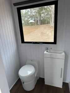 baño pequeño con aseo y ventana en The Retreat Tiny House 2, en Lagoon Pocket