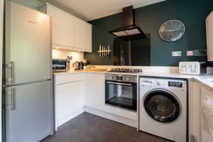 una cucina con armadi bianchi e una lavatrice/asciugatrice di Park View- 2 bed apartment close to East Surrey Hospital a Salfords