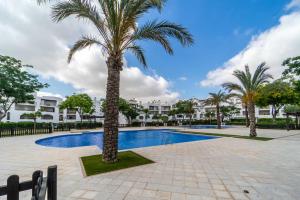 a palm tree next to a swimming pool at Elegant apartment with stunning pool views at La Torre Golf- MO2412LT in Torre-Pacheco