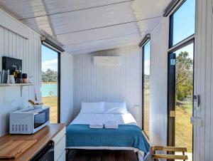 1 dormitorio en una casa pequeña con cama y ventana en Turtle Island Lakeside Tiny House en Toogoom