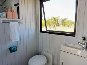 a bathroom with a toilet and a sink and a window at Turtle Island Lakeside Tiny House in Toogoom