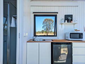 cocina con encimera, microondas y ventana en Turtle Island Lakeside Tiny House, en Toogoom