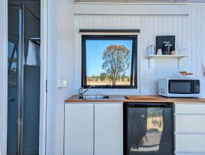 a kitchen with a counter with a microwave and a window at Turtle Island Lakeside Tiny House 2 in Toogoom