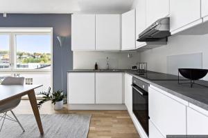 a kitchen with white cabinets and a dining table at Eksklusiv byleilighet med utsikt i Trondheim in Trondheim