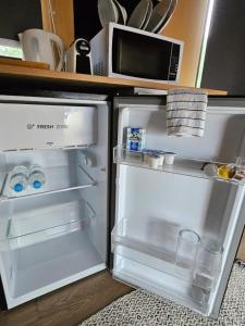 a refrigerator with its door open and a microwave at Alma Tiny House in Willunga