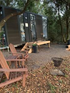 a house with two benches and a trash can in front of it at Tiny House Elevation 156-2 in Amamoor