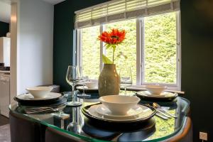 a table with plates and a vase with a flower on it at Park View- 2 bed apartment close to East Surrey Hospital in Salfords